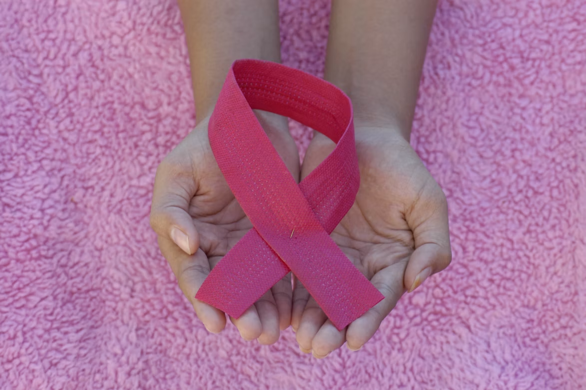 lenço rosa sobre as palmas das mãos de uma mulher