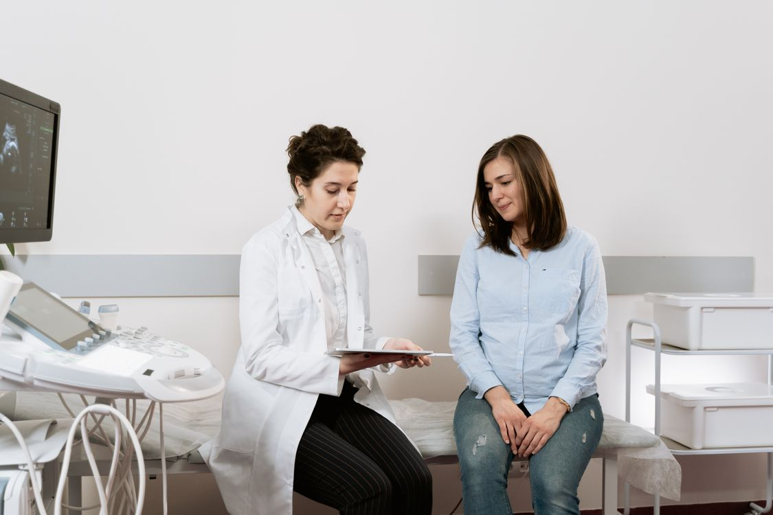 médica mostrando uma prancheta para uma paciente