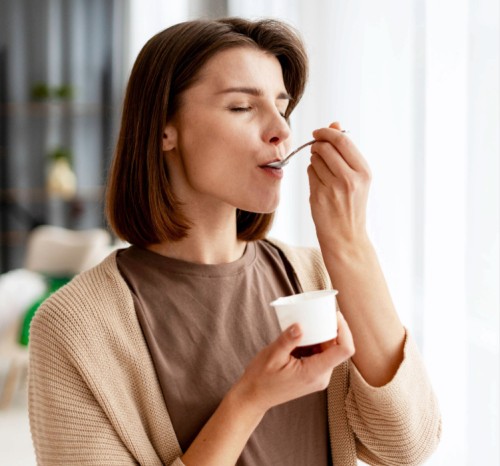 mulher degustando um doce de pote branco com uma colher